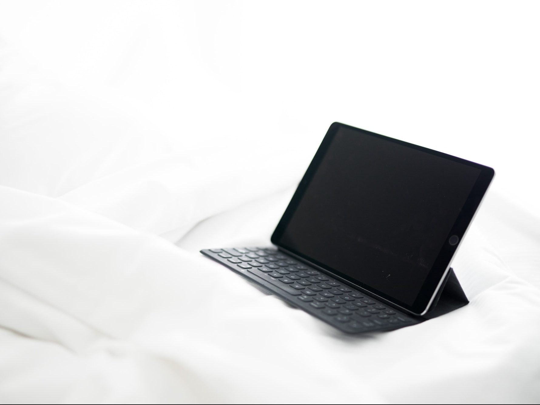 Tablet ipad computer technology tablet isolated on a empty bed with crisp white cotton sheets simple